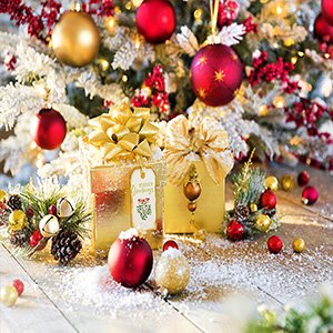 Christmas gifts and ornaments with artificial snow and a decorated tree in the background