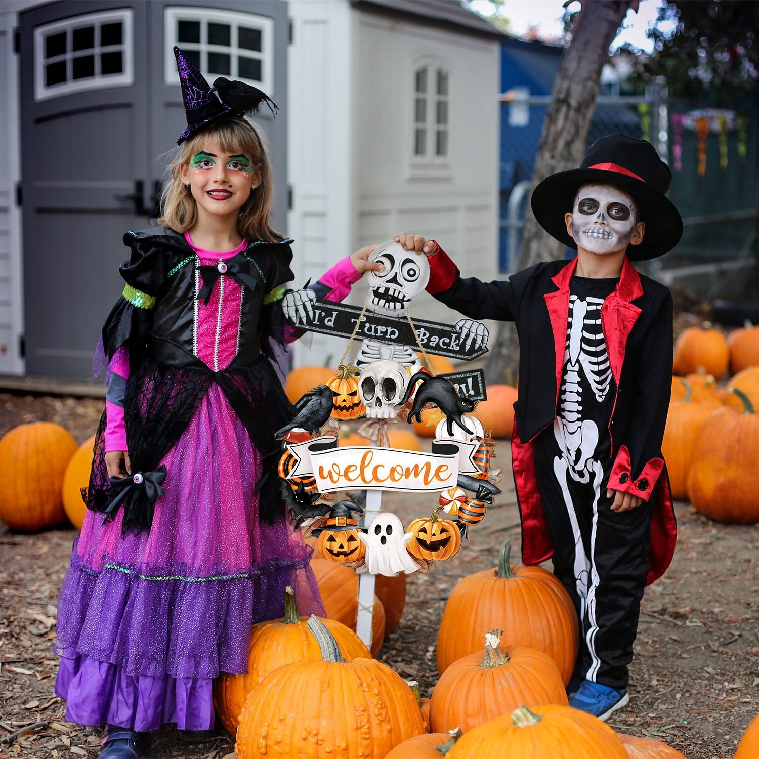Children in Halloween costumes holding a Halloween wreath sign with pumpkins and ghosts.