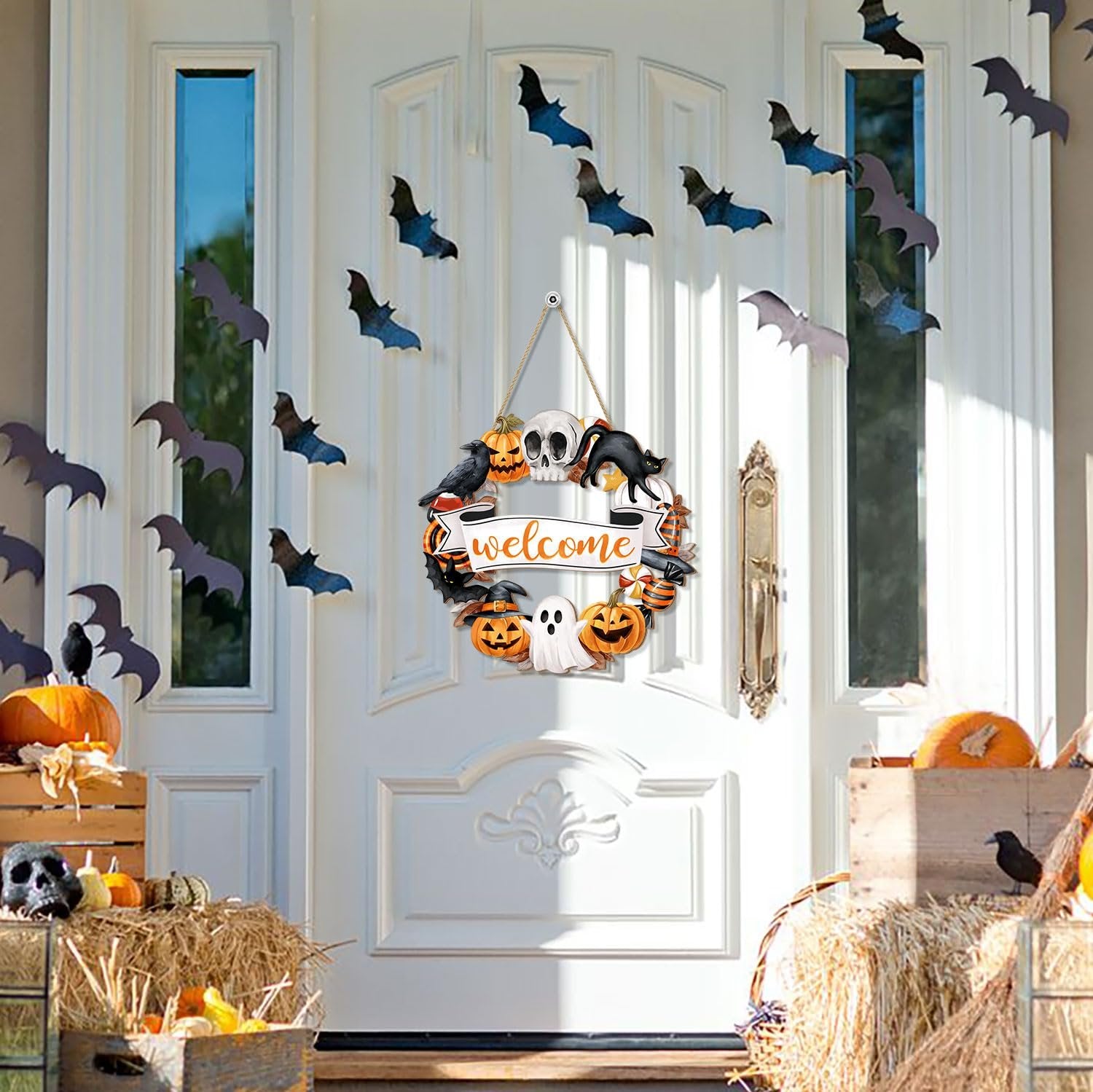 Halloween door wreath sign with ghost, pumpkin, skull, and black cat hanging on a white door with paper bats.