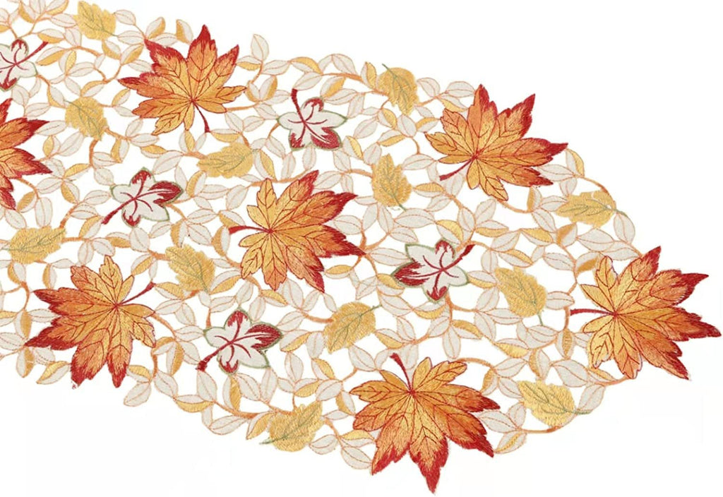 Fall table runner with embroidered maple leaves and vines on a white background, close-up view.
