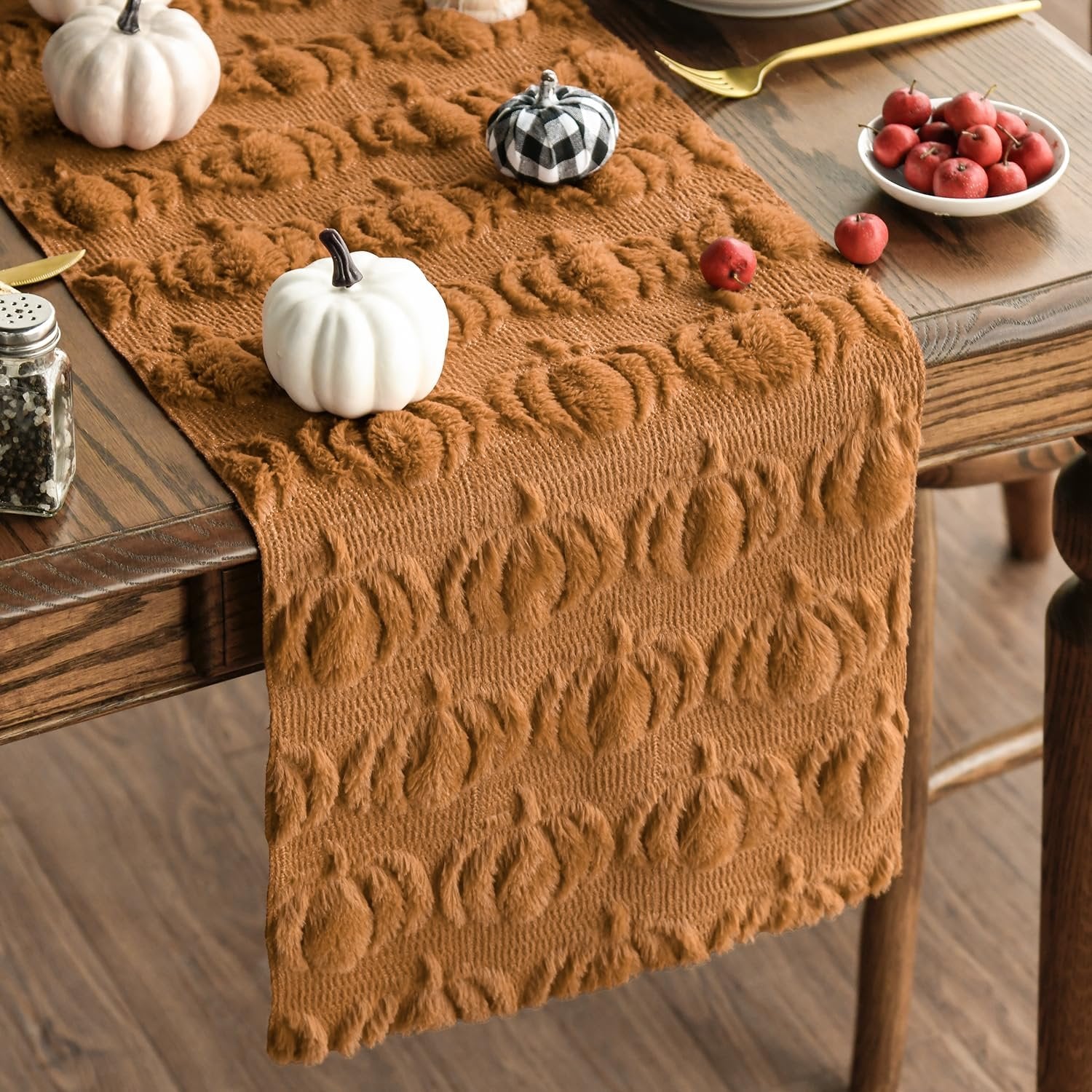 Caramel faux fur table runner with pumpkin pattern on a wooden dining table with decorative pumpkins and apples