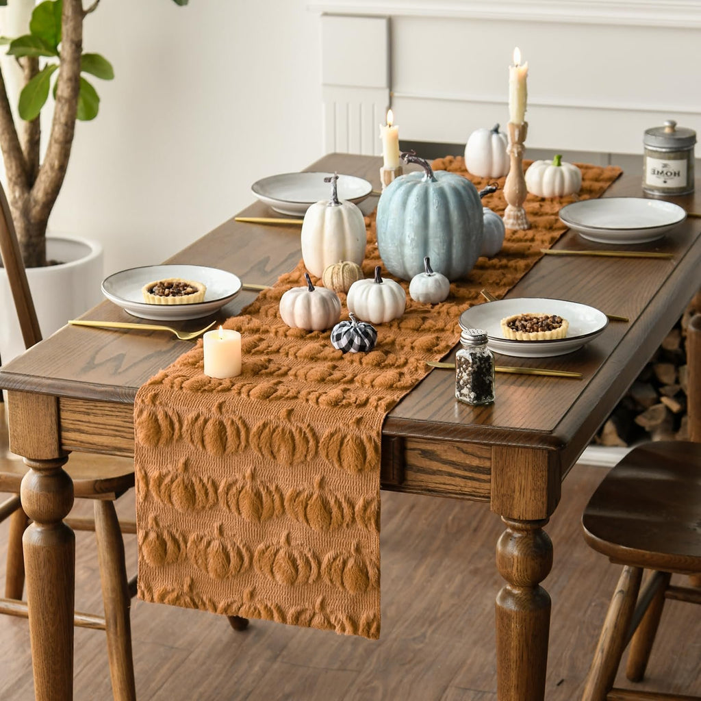 Caramel faux fur pumpkin table runner draped on a wooden dining table with place settings and pumpkins