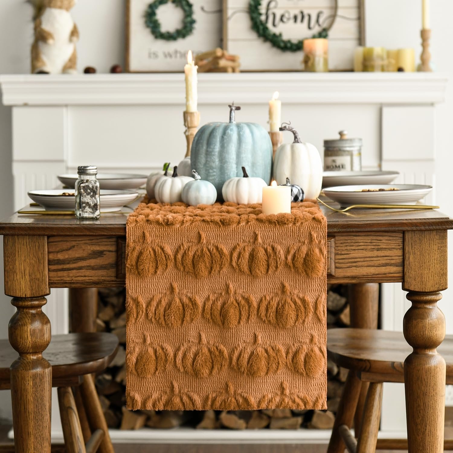 Caramel faux fur pumpkin table runner on a wooden dining table with fall decor, including pumpkins and candles.