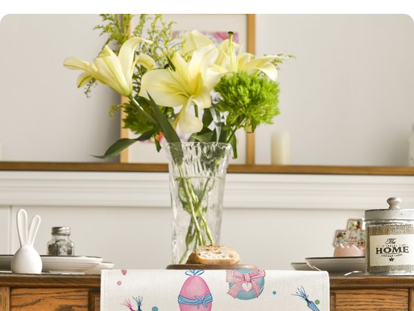 Easter table runner with watercolor eggs and carrots on a wooden table with a vase of flowers