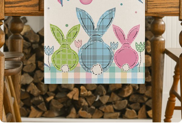 Easter table runner with three plaid bunnies and tulips, draped over a wooden table with logs in the background.