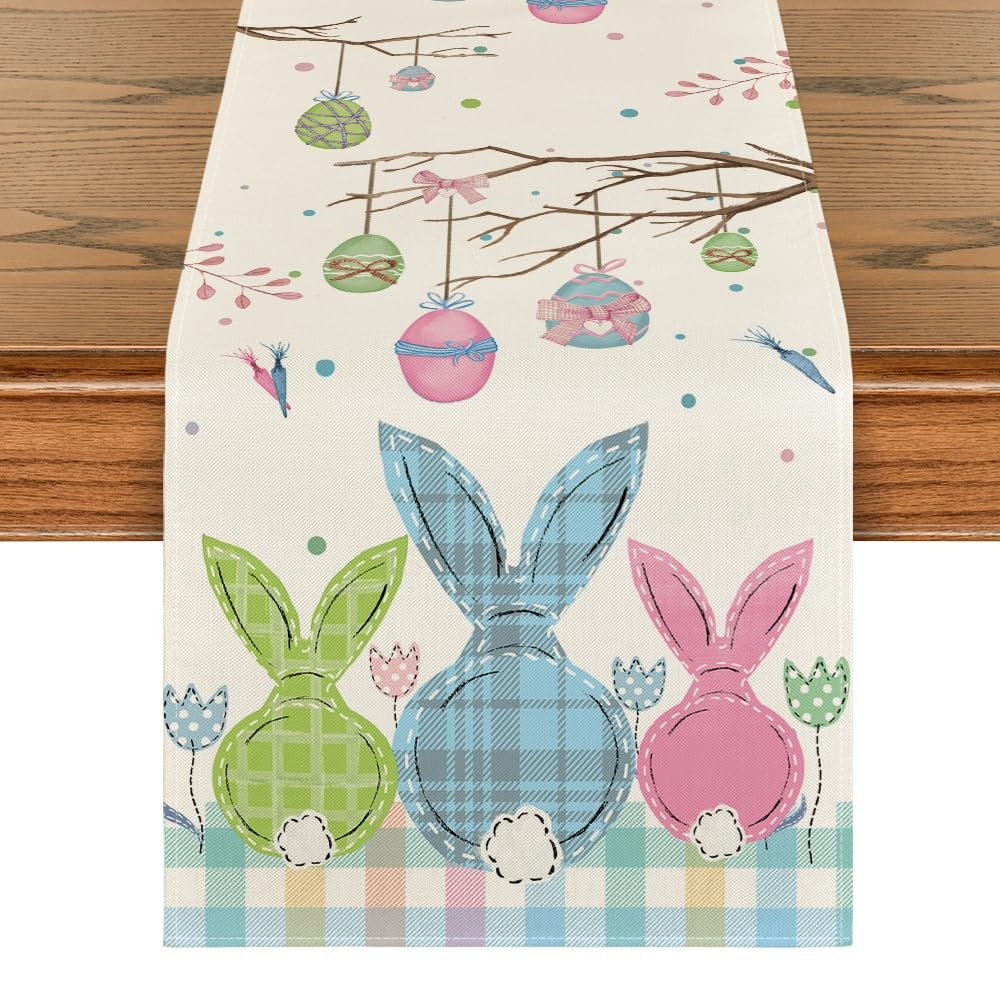 Easter table runner with plaid bunnies, hanging eggs, and flowers on a branch, laid on a wooden table.