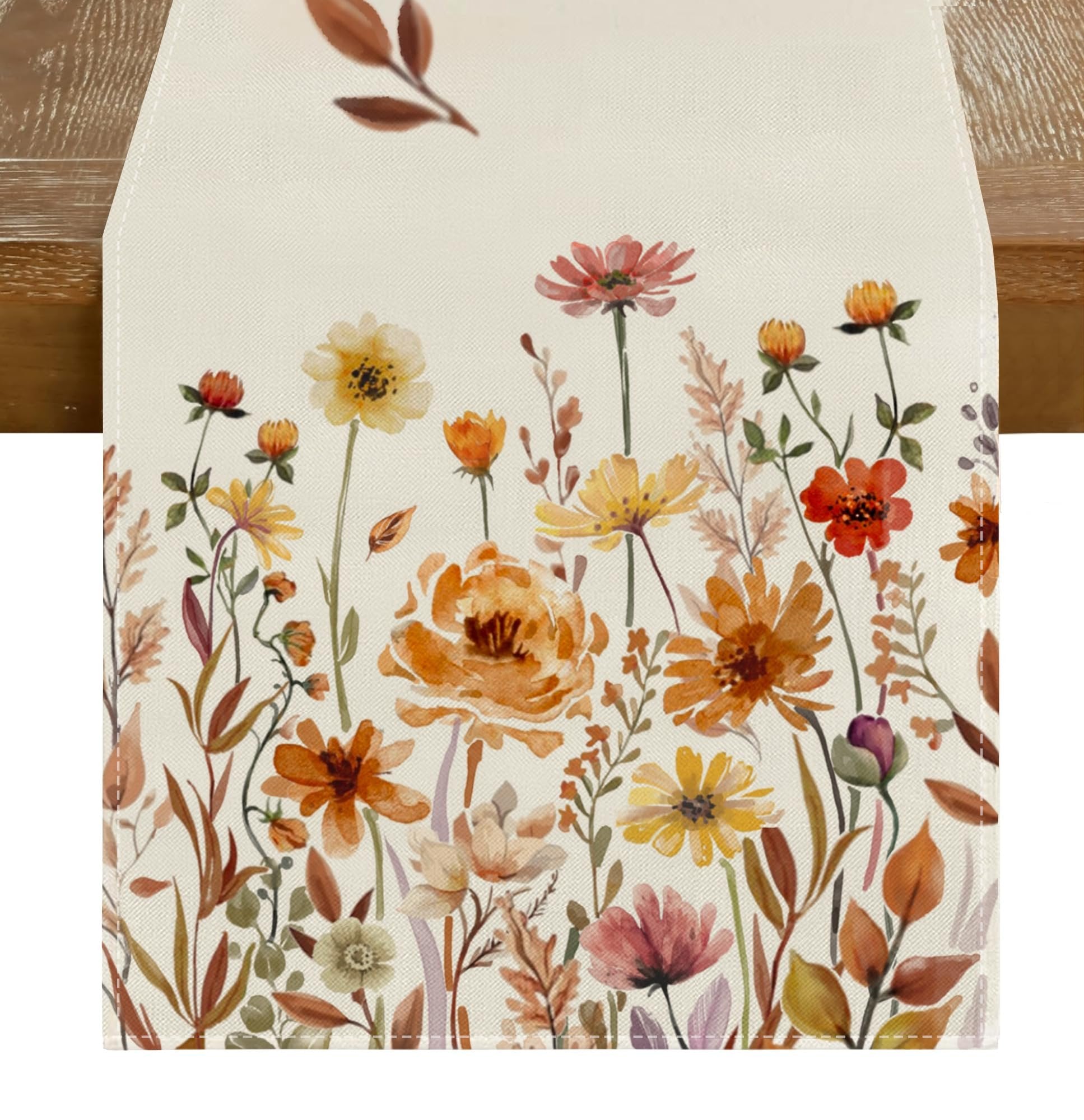 Cream table runner with a watercolor floral and leaf pattern in autumn colors, shown on a wooden table.