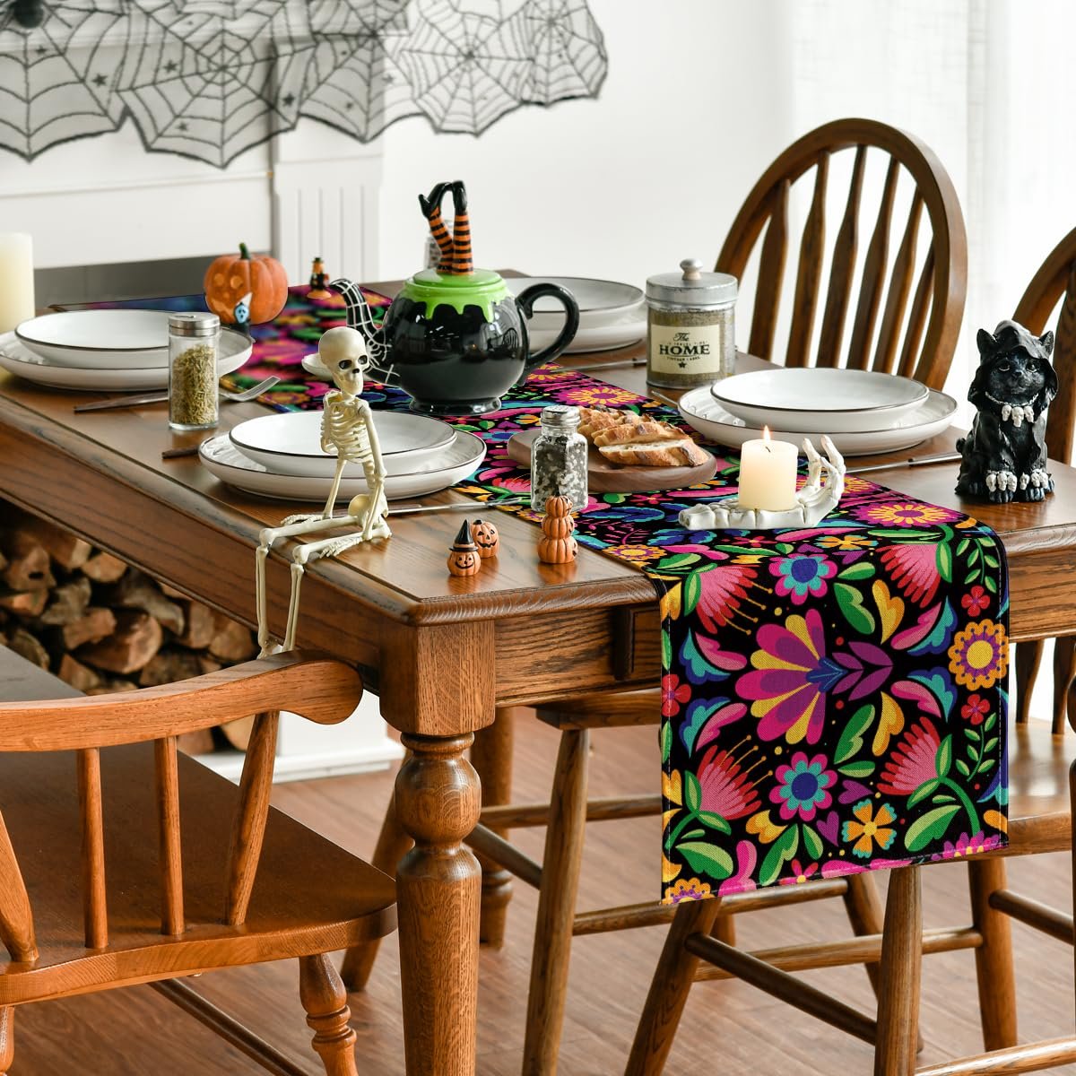 Floral table runner on a wooden dining table set for Halloween with skeleton and pumpkin decorations