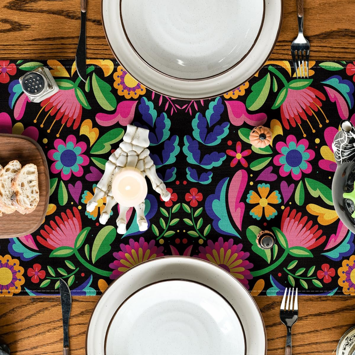 Dia de los Muertos floral table runner on a wooden table with place settings and bread
