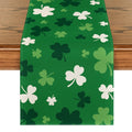 Green St. Patrick's Day table runner with scattered shamrock patterns in white and various shades of green, laid on a wooden table.