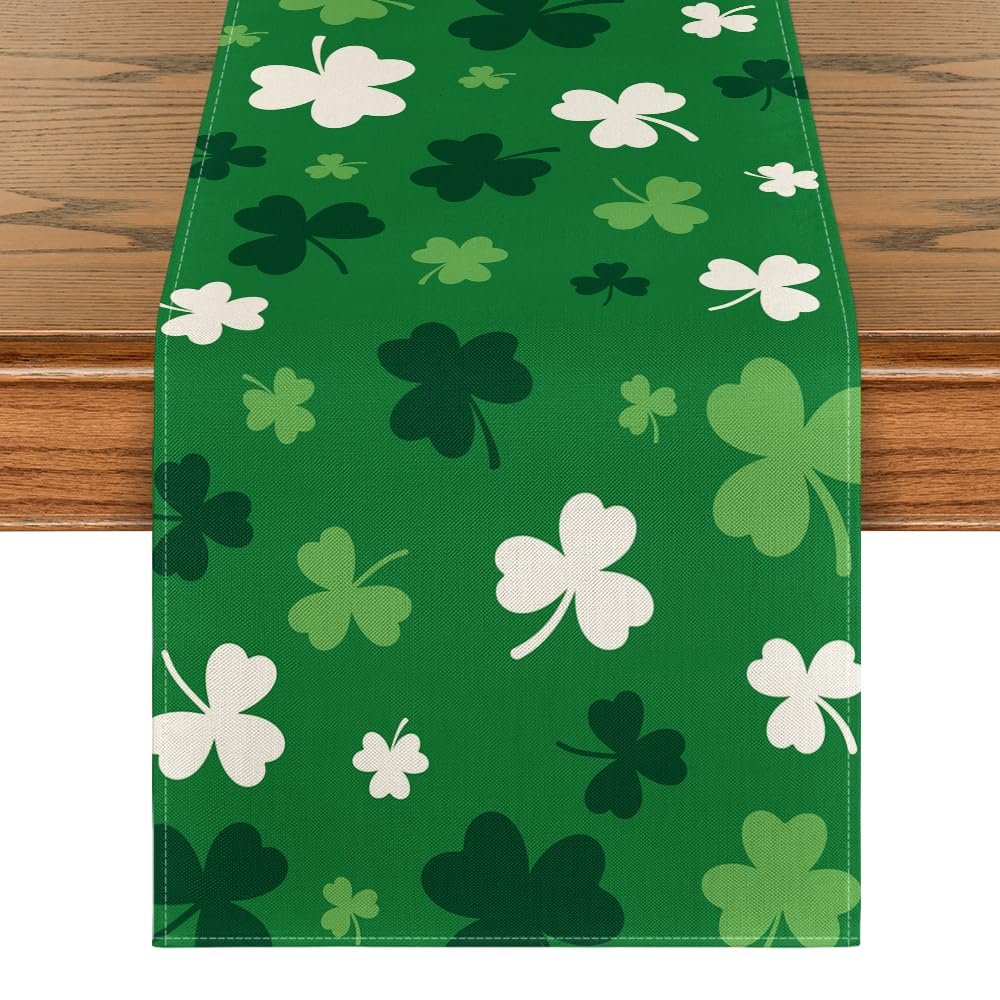 Green St. Patrick's Day table runner with scattered shamrock patterns in white and various shades of green, laid on a wooden table.