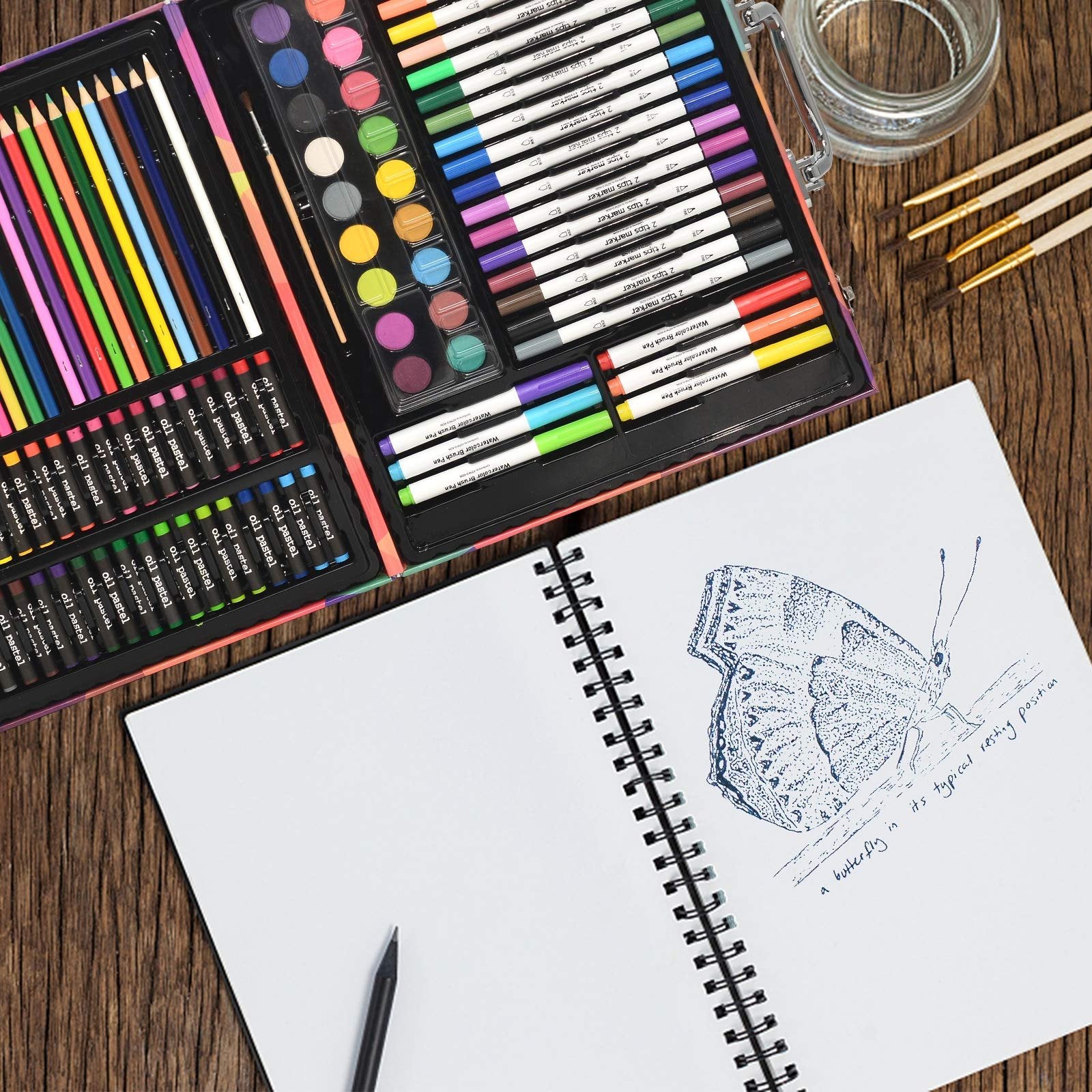 Art set contents including colored pencils, oil pastels, markers, watercolors, brushes, and a sketchbook with a butterfly drawing.