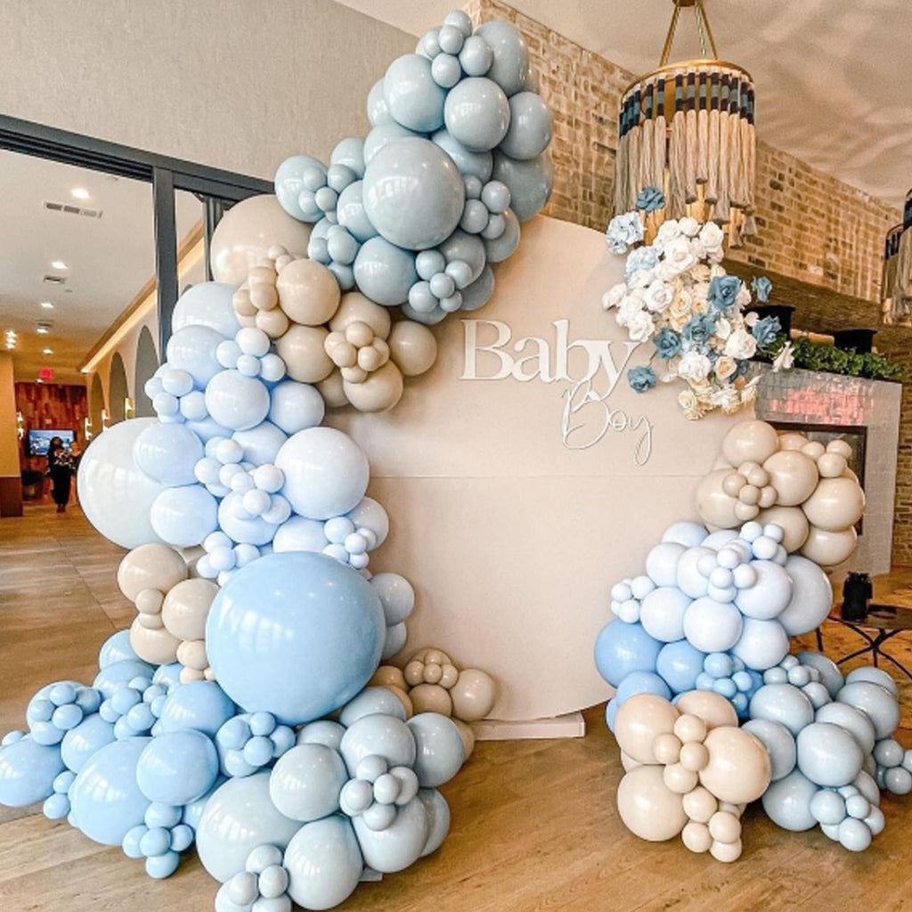 Balloon arch in dusty light blue and brown for a baby boy shower, with a circular backdrop featuring text.