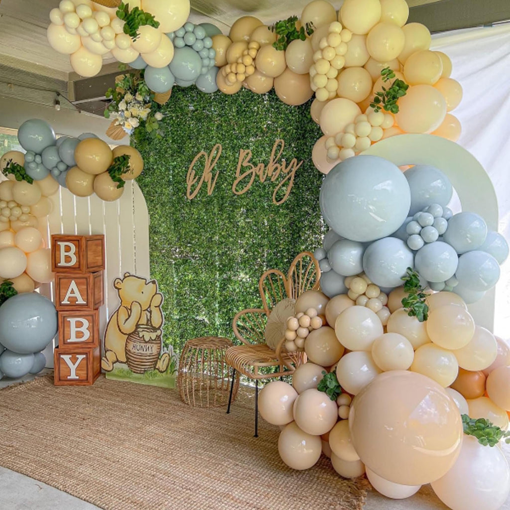 Balloon arch with dusty light blue, cream, and brown balloons, featuring a 'Oh Baby' sign and Winnie the Pooh cutout.
