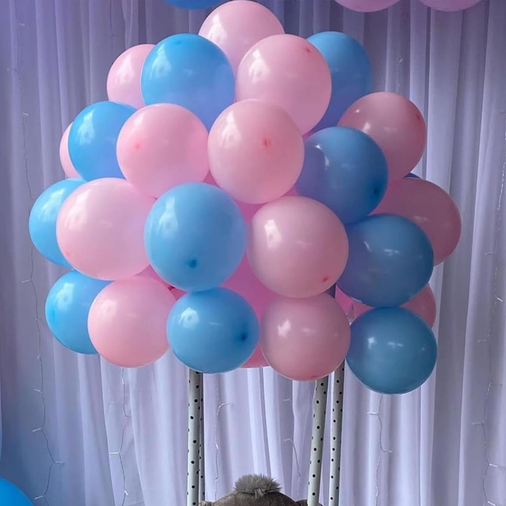 Pink and blue balloons arranged in a large cluster on a stand, with a white curtain backdrop.