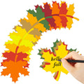 Assorted paper maple leaf cutouts in fall colors, with a hand writing 'hello fall' on one leaf.