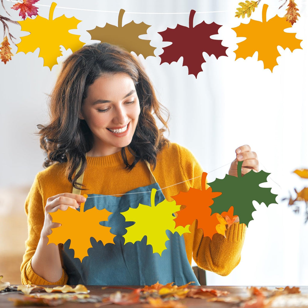 Woman holding a string of colorful paper maple leaf cutouts, creating a fall garland.