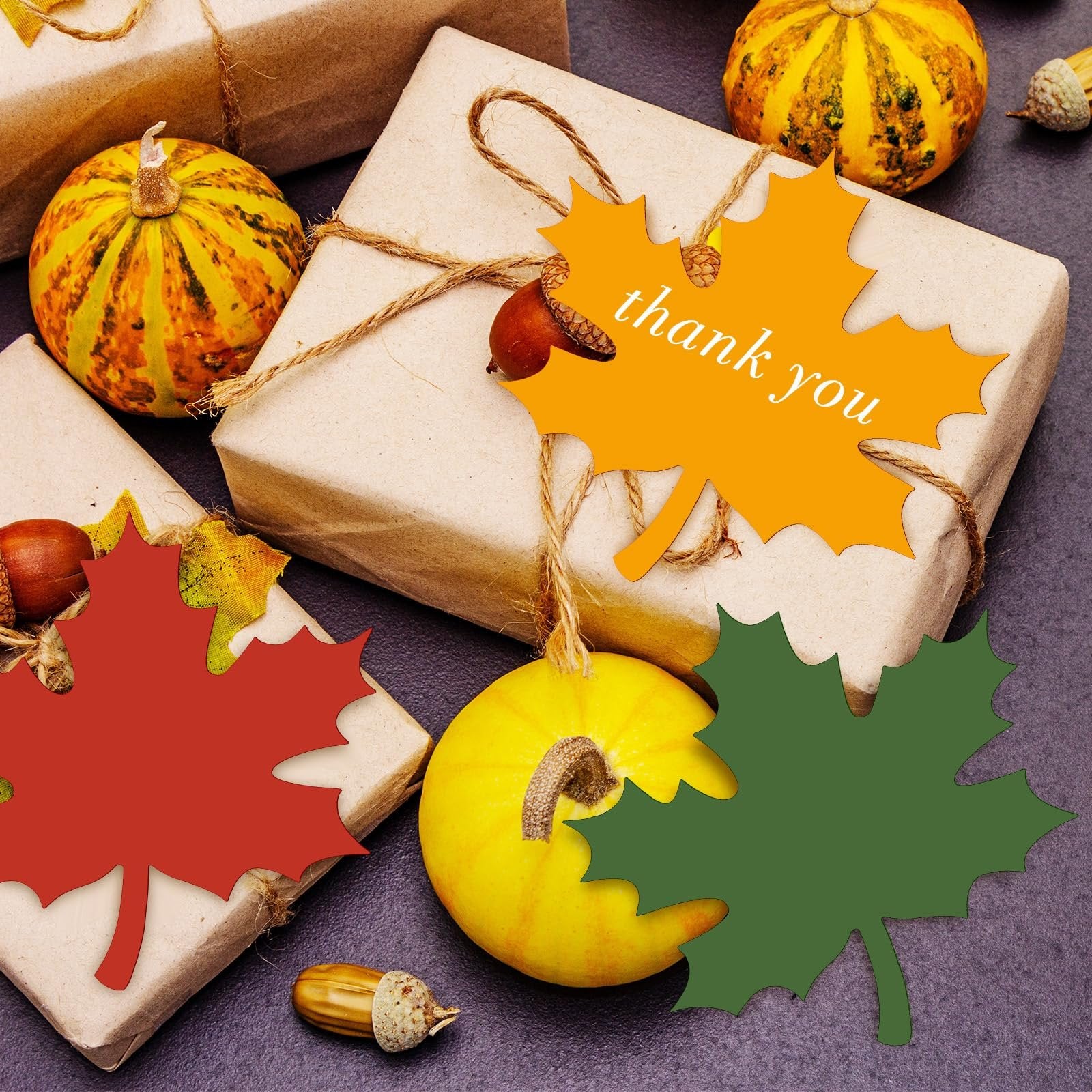 Fall-themed gifts wrapped in brown paper with decorative maple leaf cutouts and small pumpkins