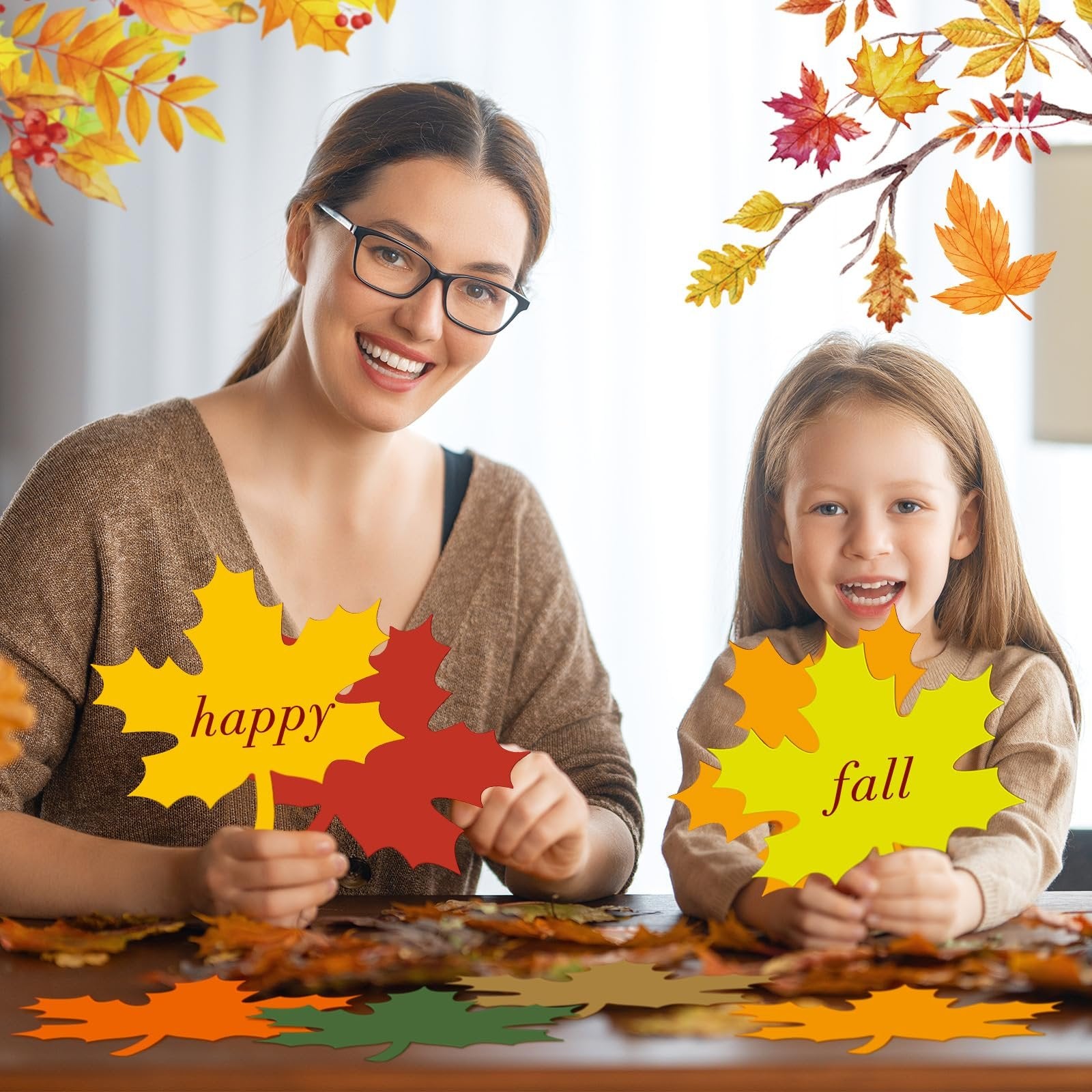 Mother and daughter holding paper maple leaf cutouts with 'happy' and 'fall' text, surrounded by autumn leaves.