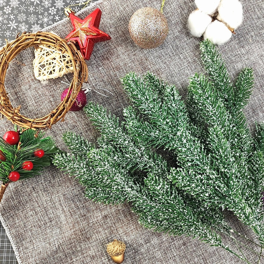 Artificial snow-frosted pine branches with Christmas ornaments and a small wreath