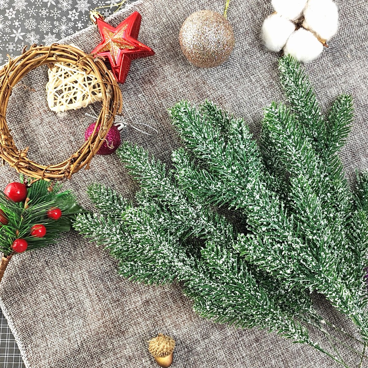 Artificial snow-frosted pine branches with Christmas ornaments and a small wreath