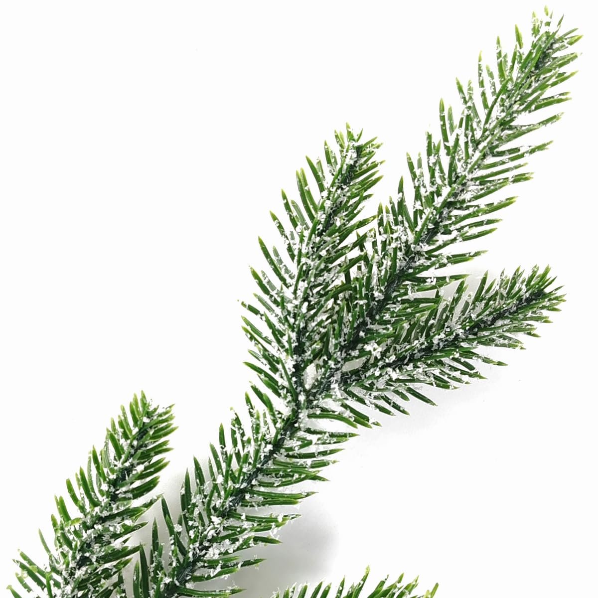Snow-frosted artificial pine branches on a white background, close-up view