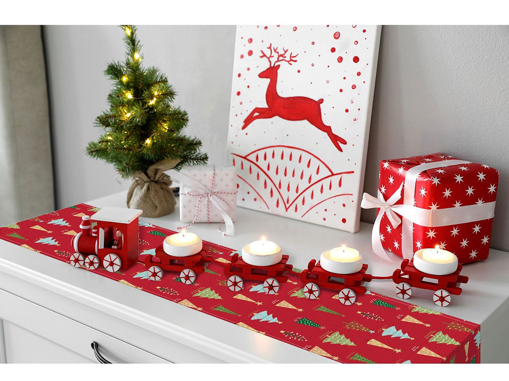 Christmas table runner with red train and candle holders on a dresser with a small tree and gifts