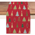 Red Christmas table runner with a pattern of various decorated pine trees, laid on a wooden surface.
