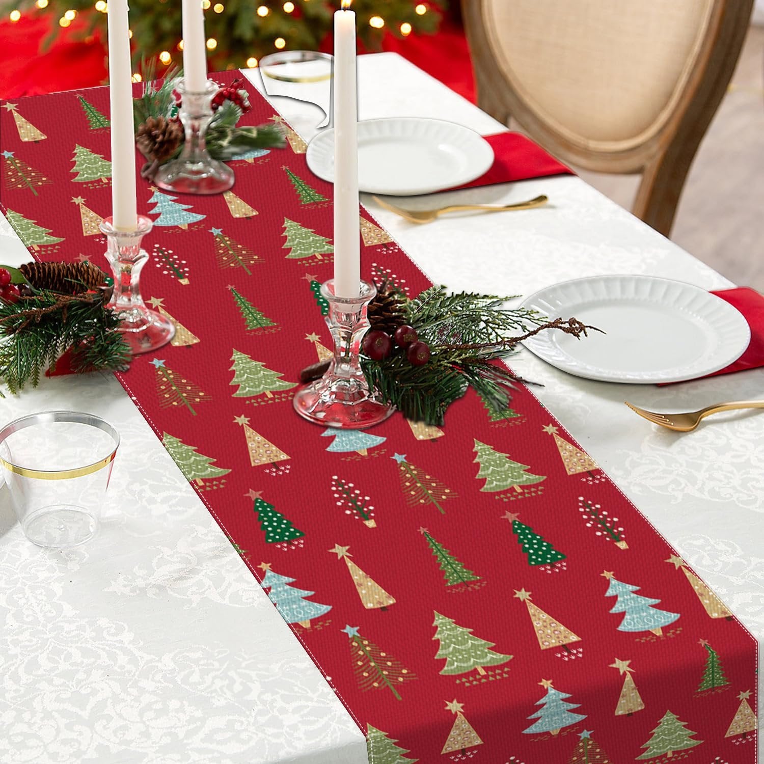 Christmas table runner with red pine trees pattern on a decorated dining table with candles and plates.