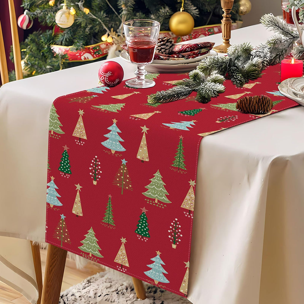 Red Christmas table runner with a pattern of various green, blue, and gold Christmas trees, laid on a table with festive decorations.