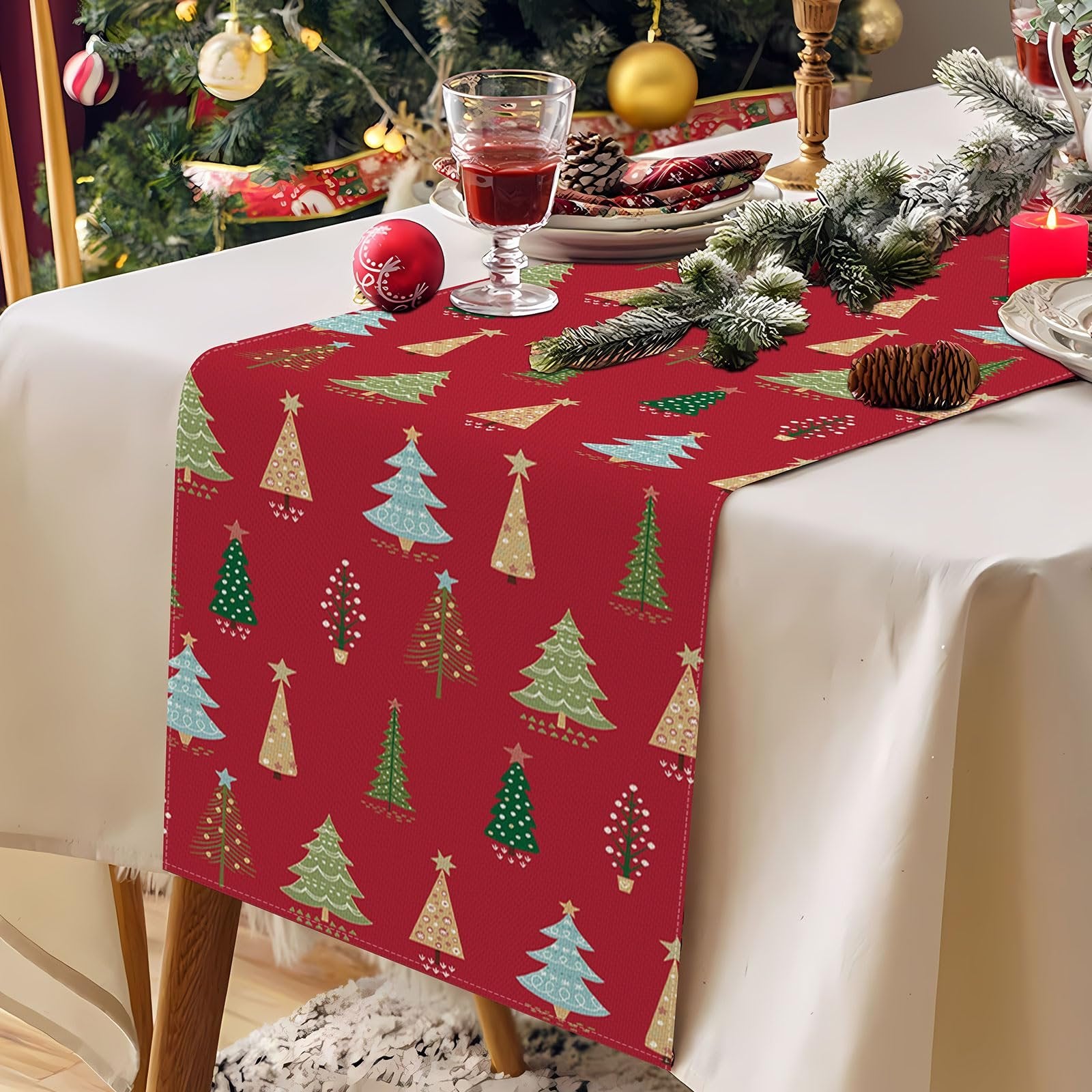 Red Christmas table runner with a pattern of various green, blue, and gold Christmas trees, laid on a table with festive decorations.