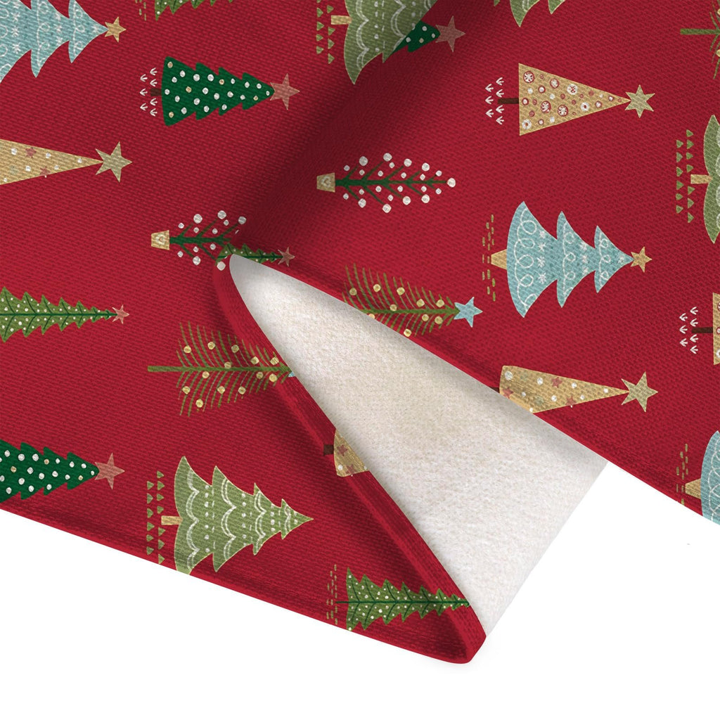 Christmas table runner with red background and various pine tree designs, showing the textured fabric and underside.