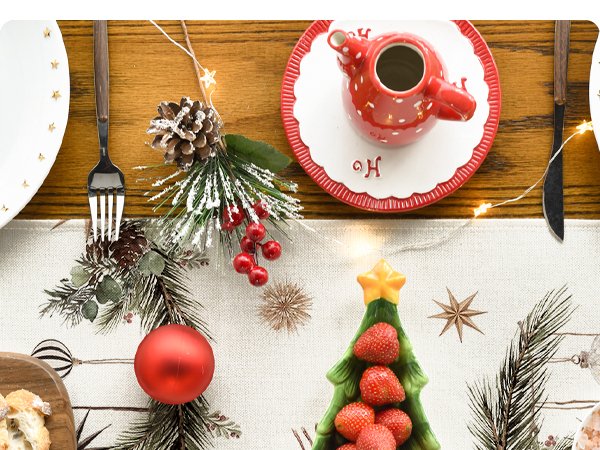 Christmas table runner with pine cones, berries, and a strawberry tree dish, set for a meal.