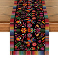 Colorful Day of the Dead serape table runner with birds and floral patterns on a wooden table.