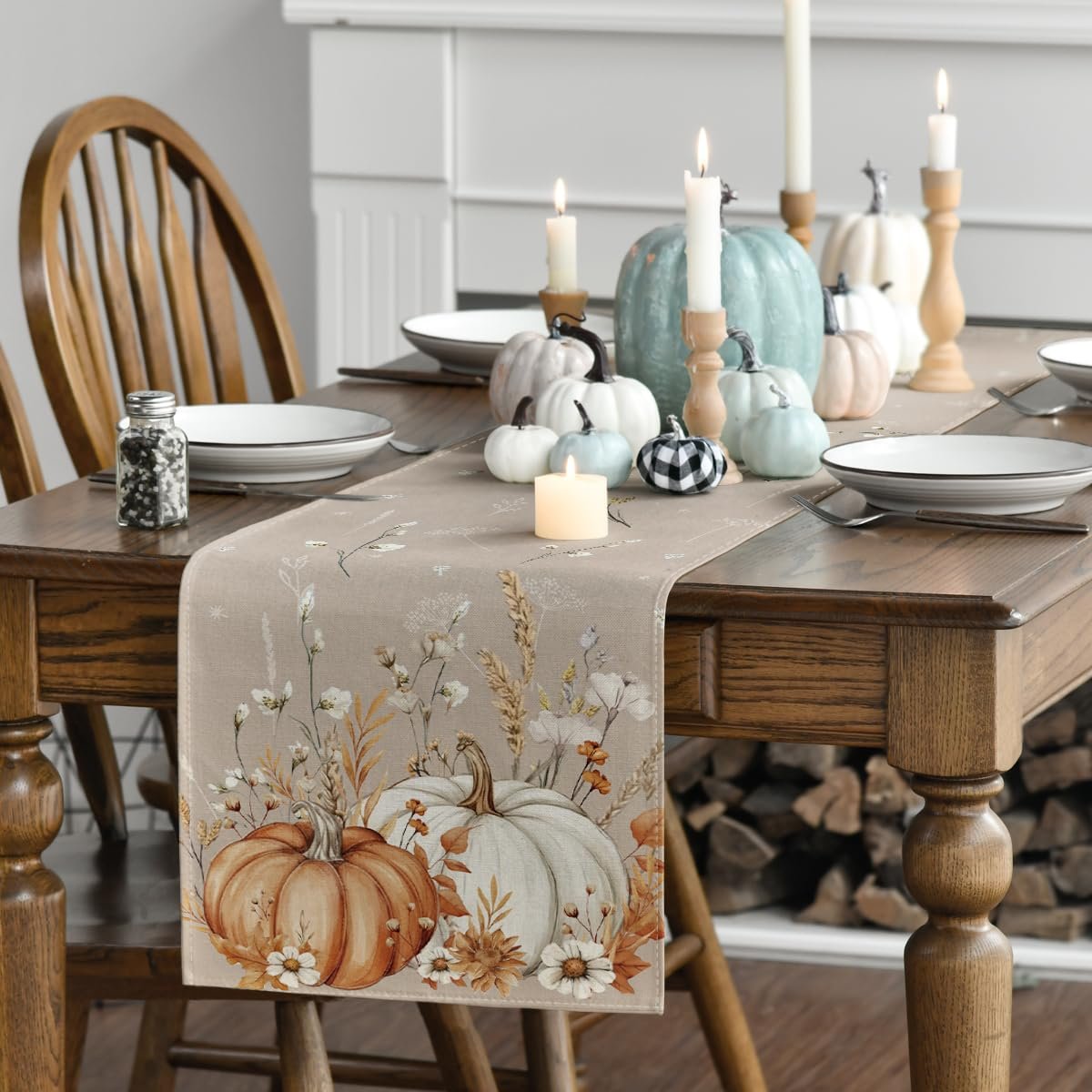 Fall table runner with pumpkins and floral print laid on a wooden dining table with place settings and candles