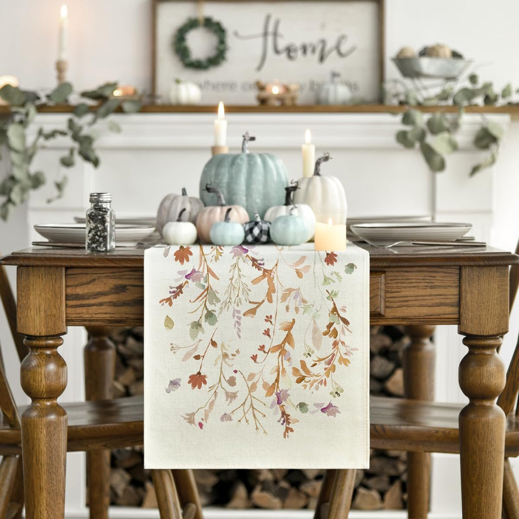 Fall table runner with floral leaves pattern on a decorated dining table with pumpkins and candles
