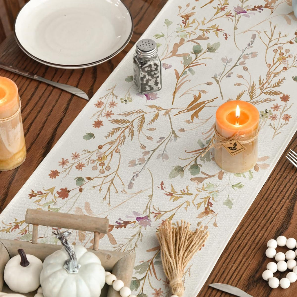 Table runner with floral leaves pattern on a wooden table with candles and pumpkins