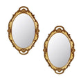 Two antique gold oval decorative wall mirrors with ornate frames on a white background.