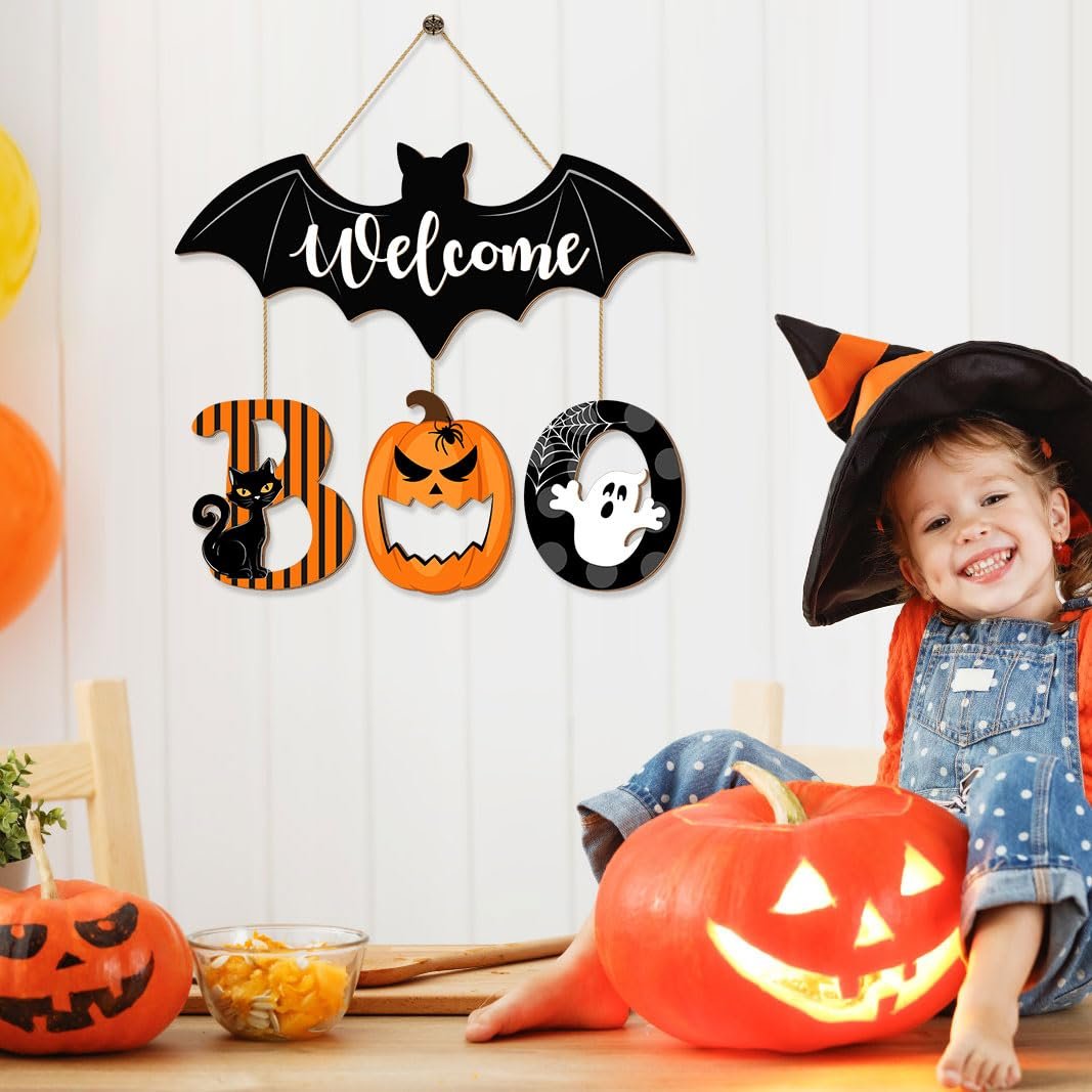 Halloween BOO door sign with bat, cat, pumpkin, and ghost ornaments, hanging on a wall with a child and pumpkins nearby.