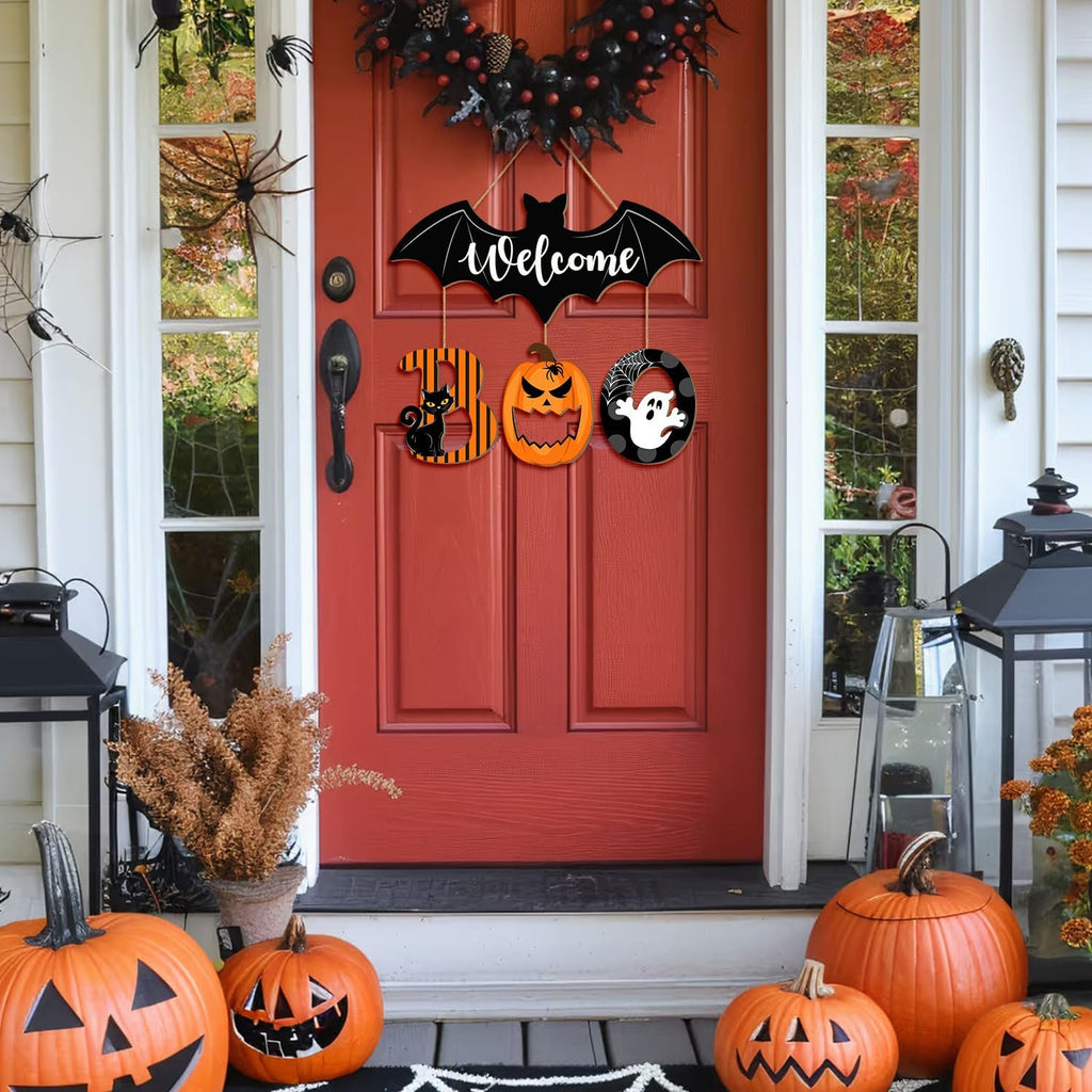 Halloween BOO door sign with bat, cat, pumpkin, and ghost ornaments hanging on a red door with pumpkins and lanterns on the porch.