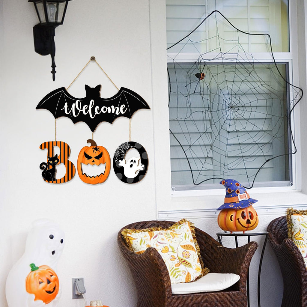 Halloween BOO door sign with bat, cat, pumpkin, and ghost ornaments hanging on a wall next to a window with a spiderweb.