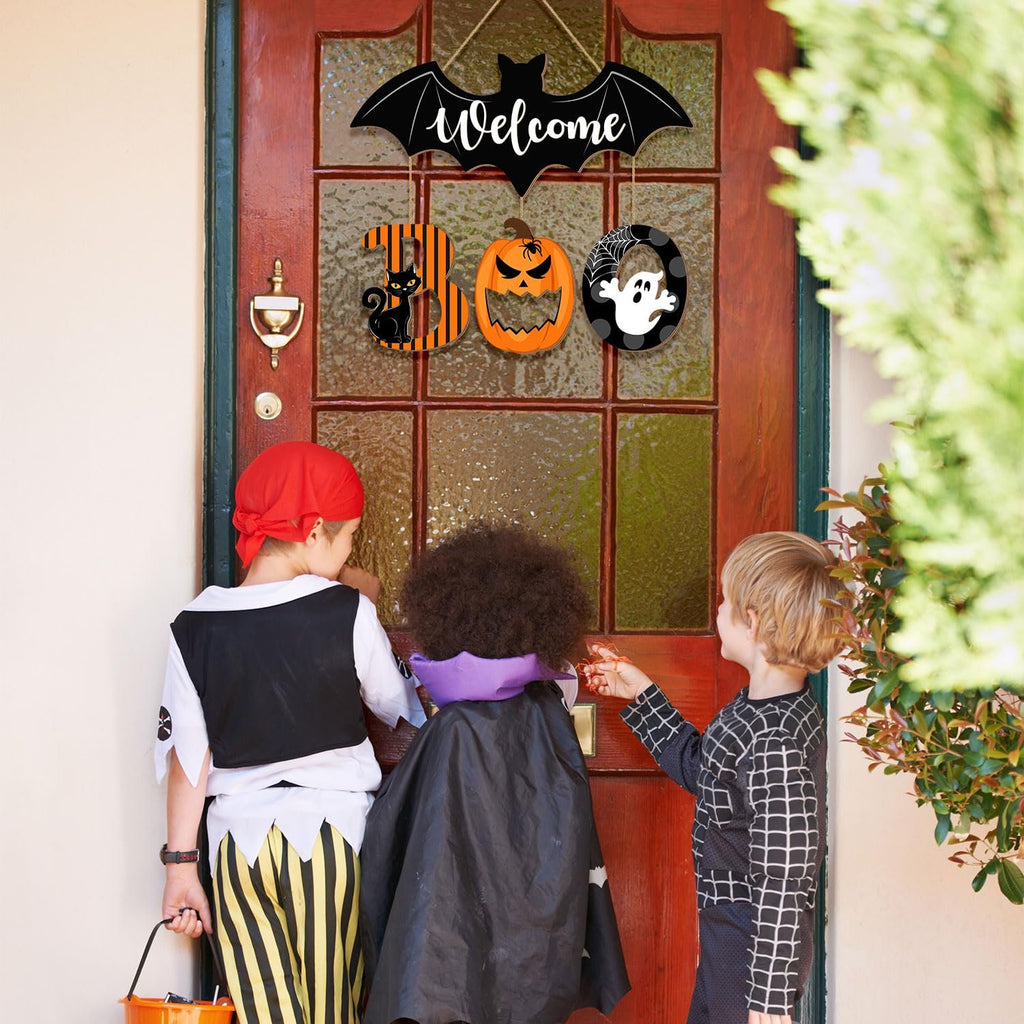 Halloween BOO door sign with bat, cat, pumpkin, and ghost ornaments hanging on a wooden door with children in costumes.