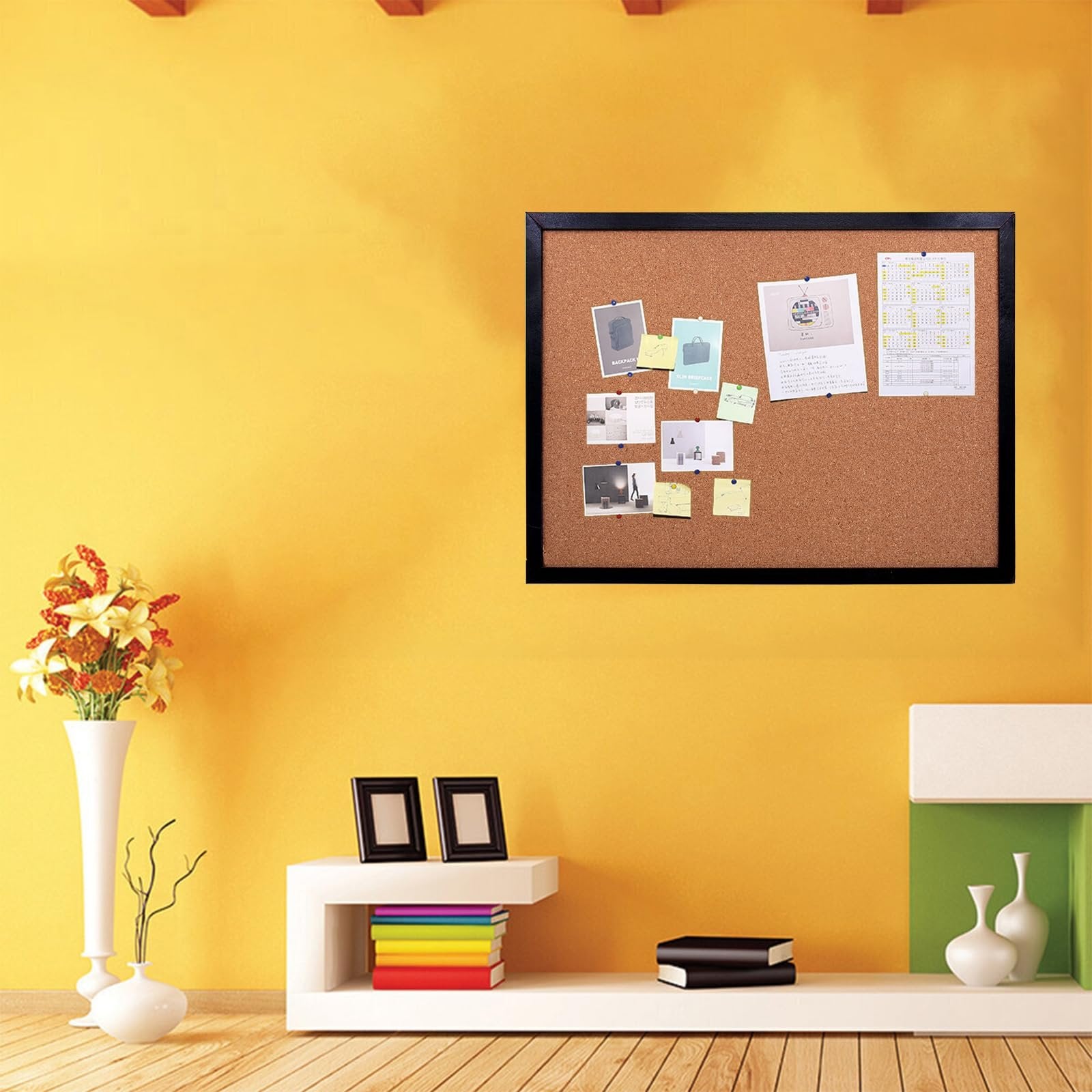 Black cork bulletin board with oak wood finish frame mounted on a yellow wall, decorated with various pinned photos and notes.