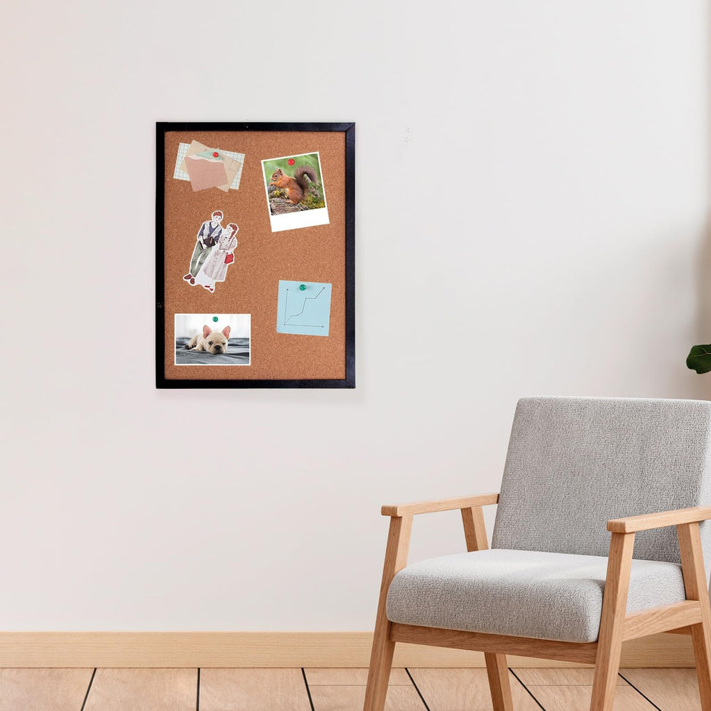 Black cork bulletin board with oak wood finish frame mounted on a wall, decorated with photos and stickers.