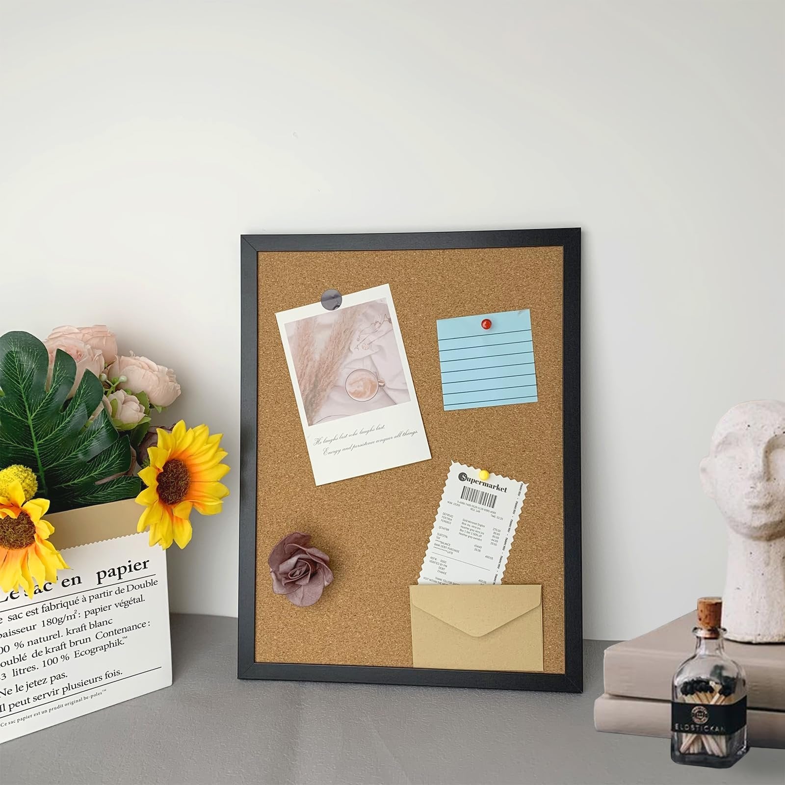 Black cork bulletin board with oak wood finish frame, decorated with photos, notes, and flowers.