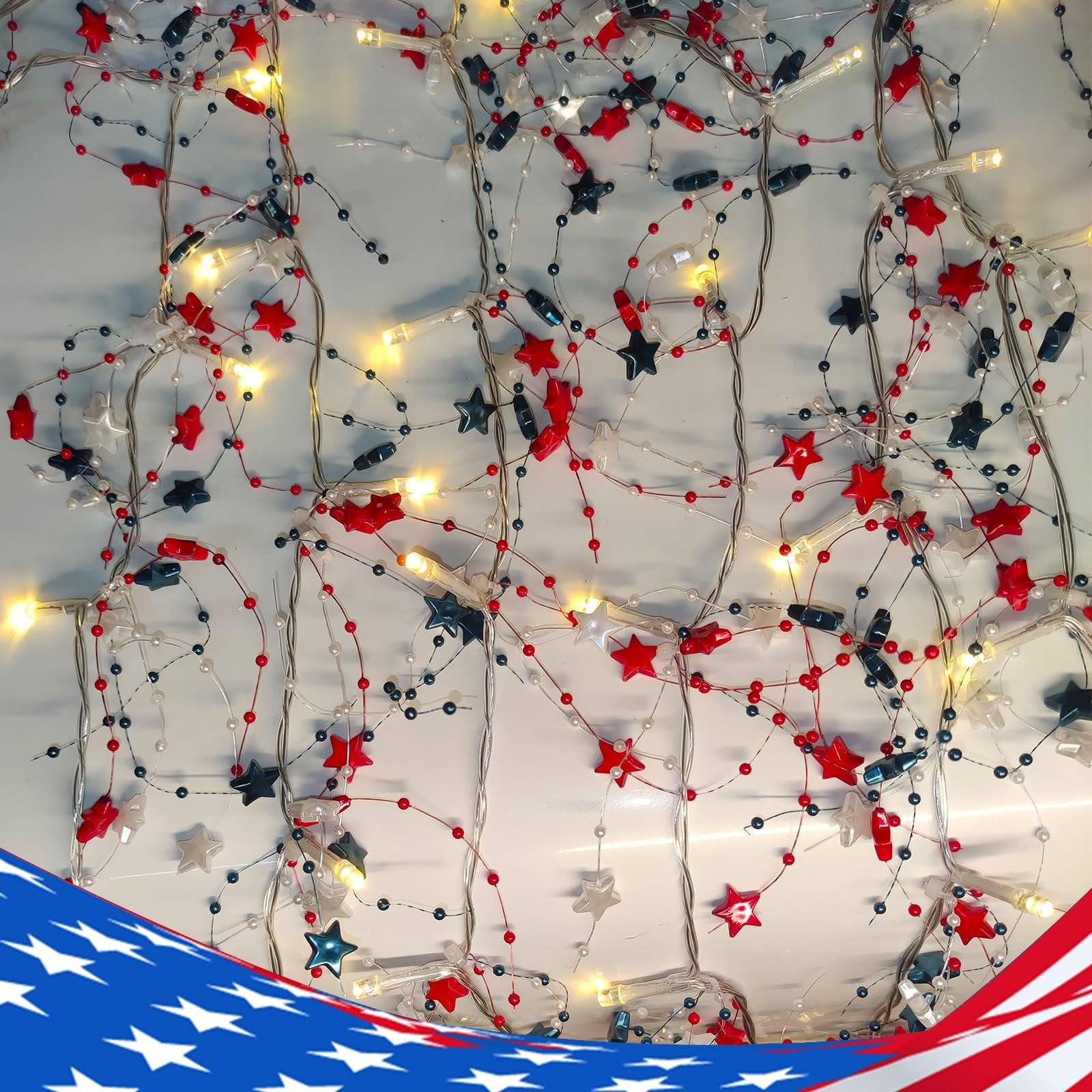 Red, white, and blue star garland with warm white LED lights, close-up view showing beaded strands and star-shaped ornaments.