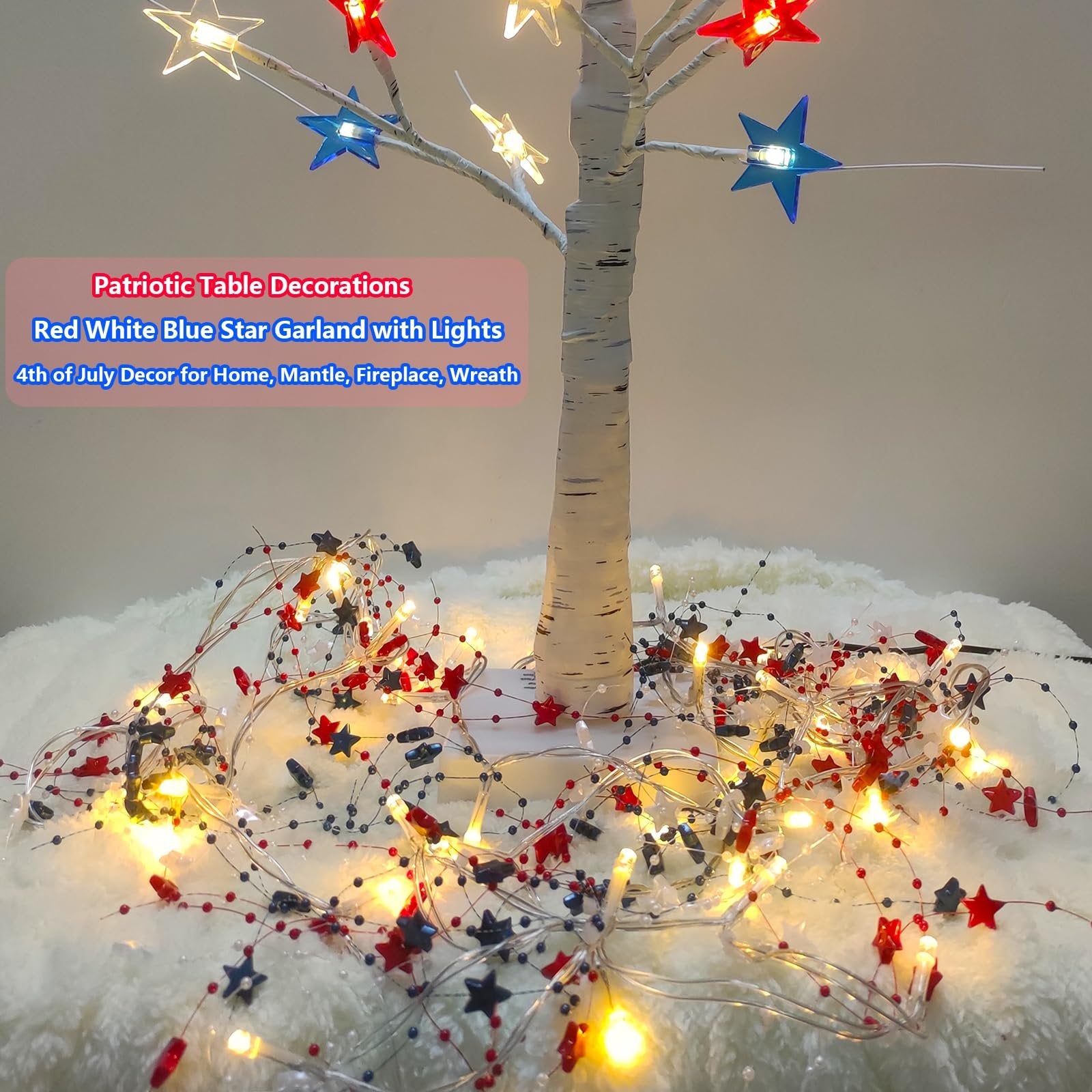 Red, white, and blue star garland with warm white LED lights draped around a white tree trunk and on a fluffy white surface.