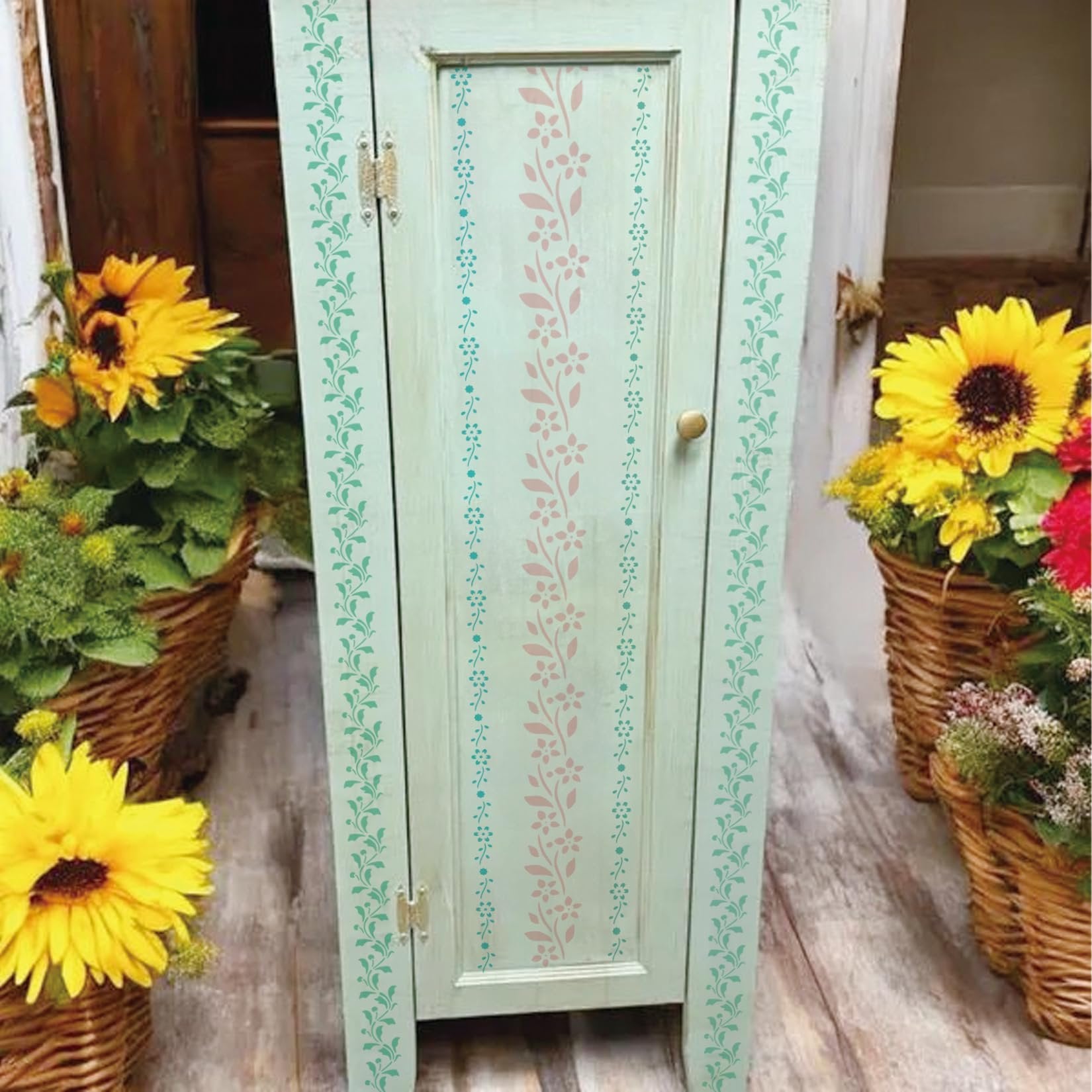 Floral border stencils applied to a light green cabinet door with sunflowers in baskets on either side.
