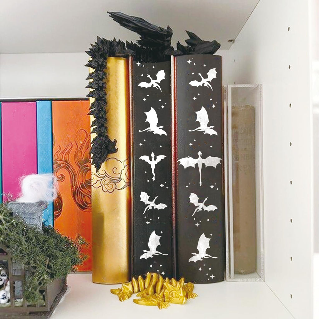Dragon vine leaf stencils on black book spines with white dragon and star designs, displayed on a shelf.