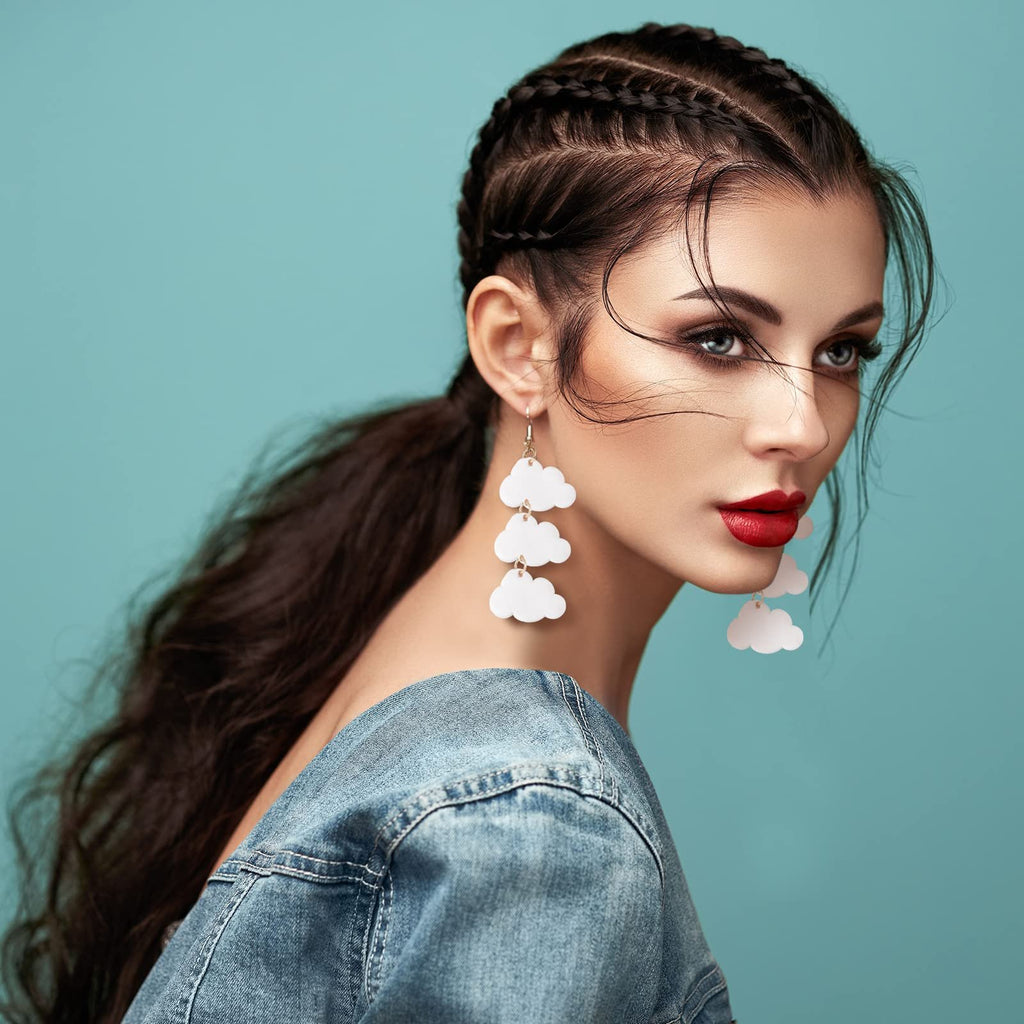Woman wearing cloud-shaped earrings and a denim jacket against a teal background